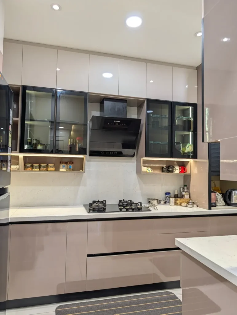 Completed modular kitchen in a Bengaluru 3 BHK with high-gloss shutters, black-framed glass cabinets, chimney and quartz countertop by Aladi Interiors