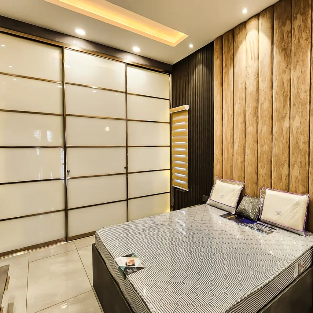 Completed bedroom in a Gulbarga villa with lacquered glass sliding wardrobe, bronze profiles and textured wall panelling by Aladi Interiors