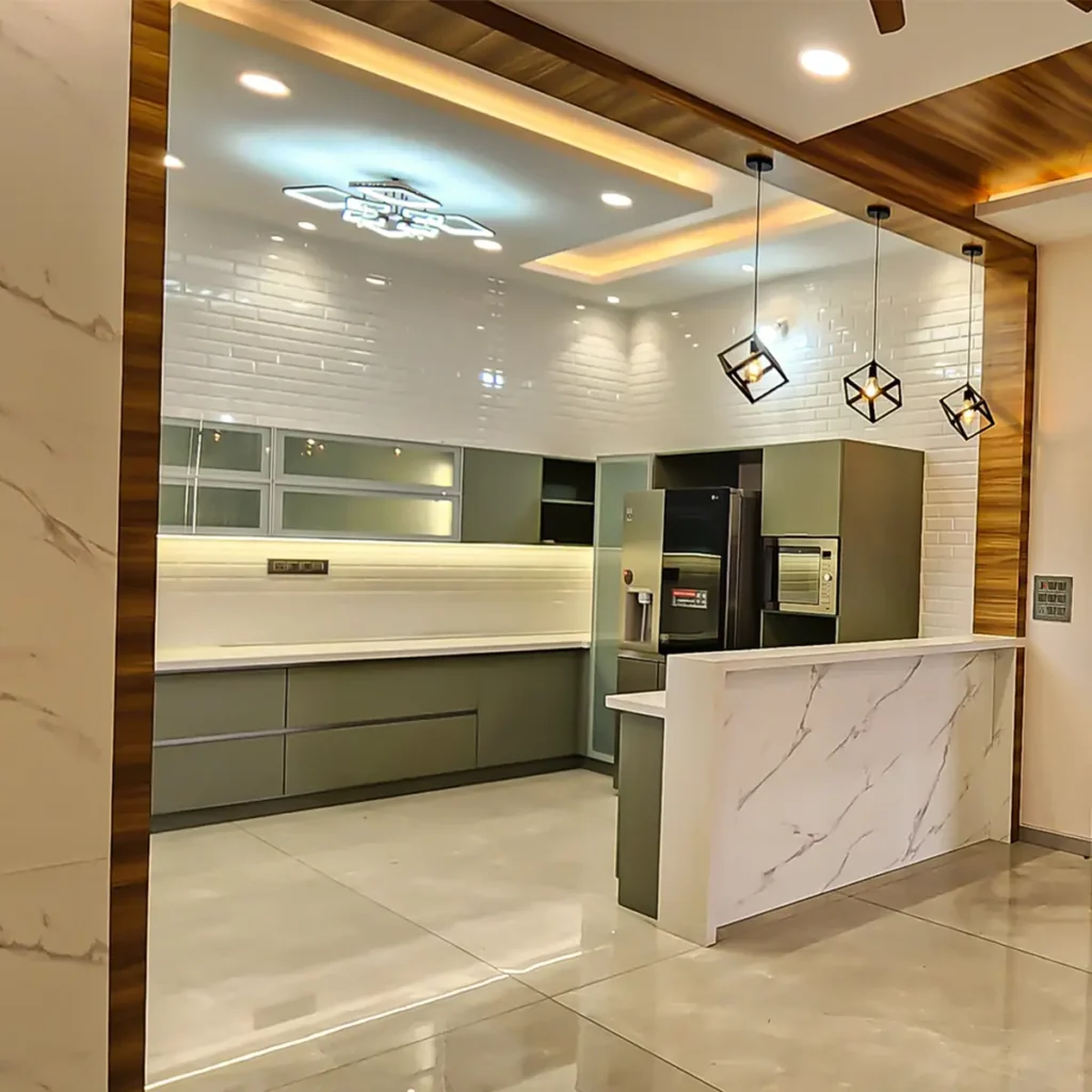 Completed open modular kitchen in a Gulbarga villa with sage green cabinets, subway tile wall, marble breakfast counter and pendant lights by Aladi Interiors