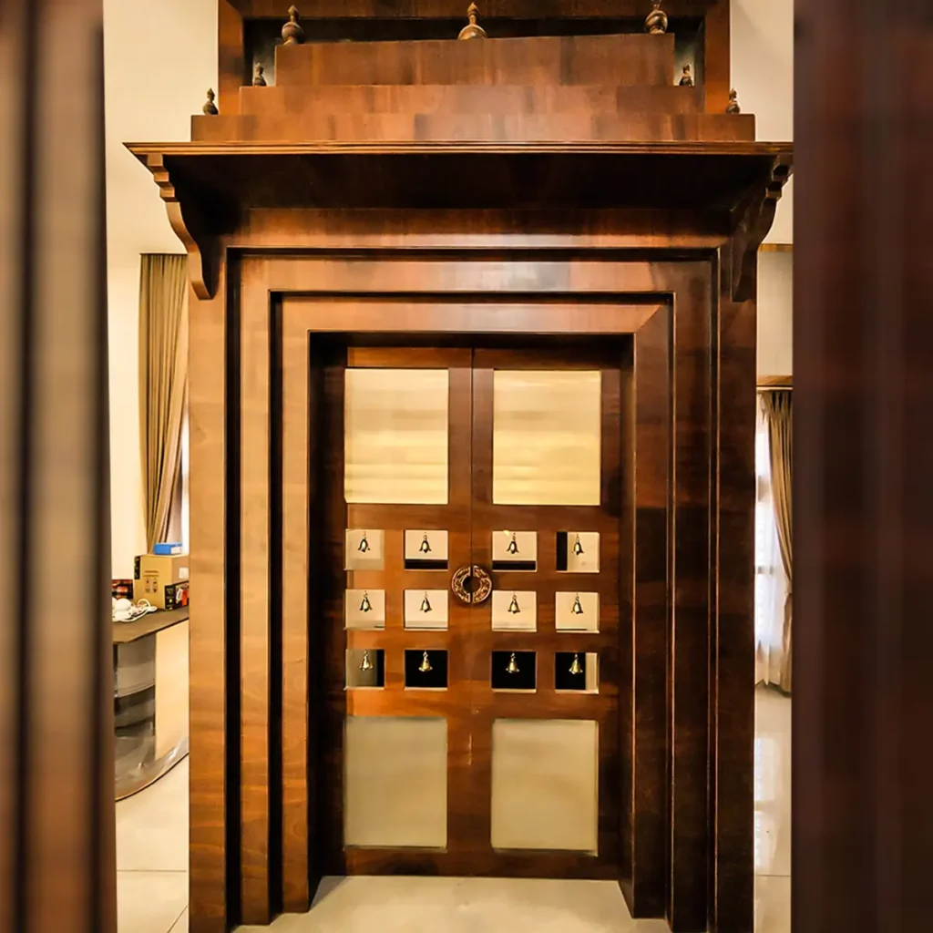 Completed temple-style wooden pooja room with brass bells and tiered top in a Gulbarga villa by Aladi Interiors
